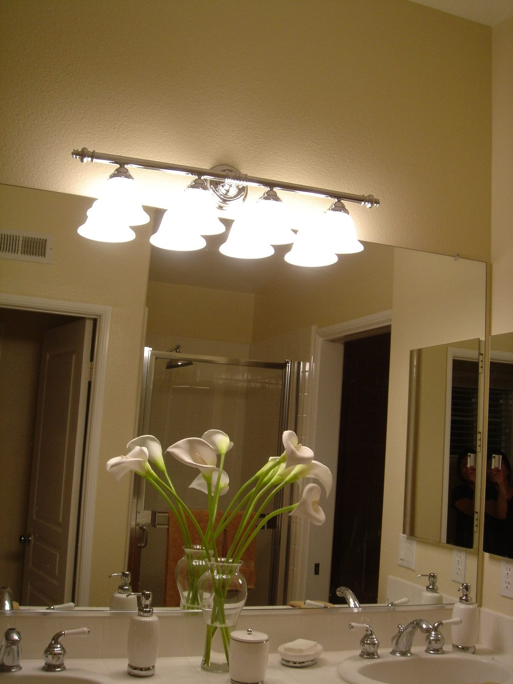 New vanity light fixture installed above a master bathroom mirror