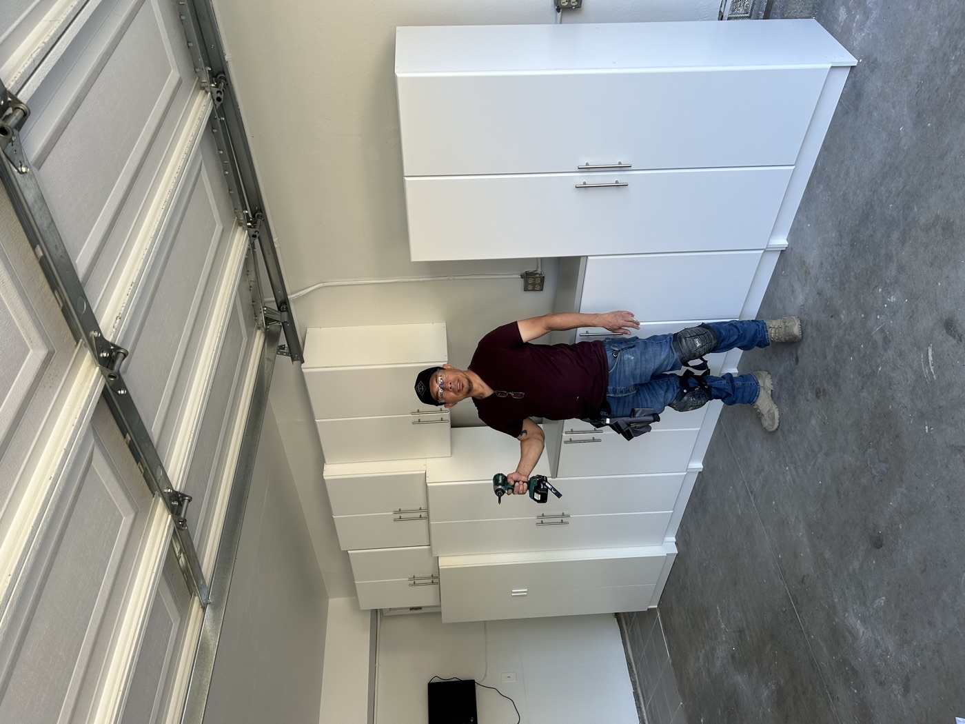 Jose Vasquez installing garage storage cabinets with a drill